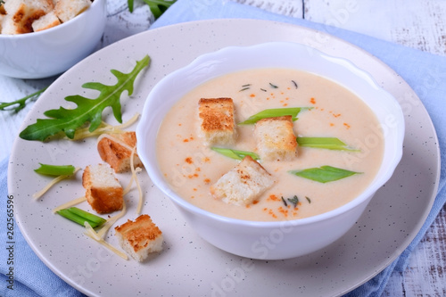 Cream soup with croutons, green onion and cheese in a white bowl