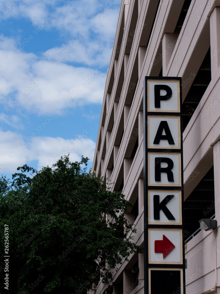 Park sign outside of a parking garage on a blue sky cloudy day Park sign outside of a parking garage on a blue sky cloudy day