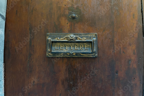 Old fashioned brass postbox on a wooden door