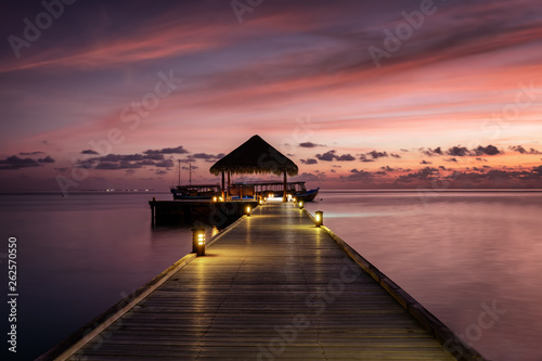 Holzsteg in den tropischen Sonnenuntergang auf den Malediven