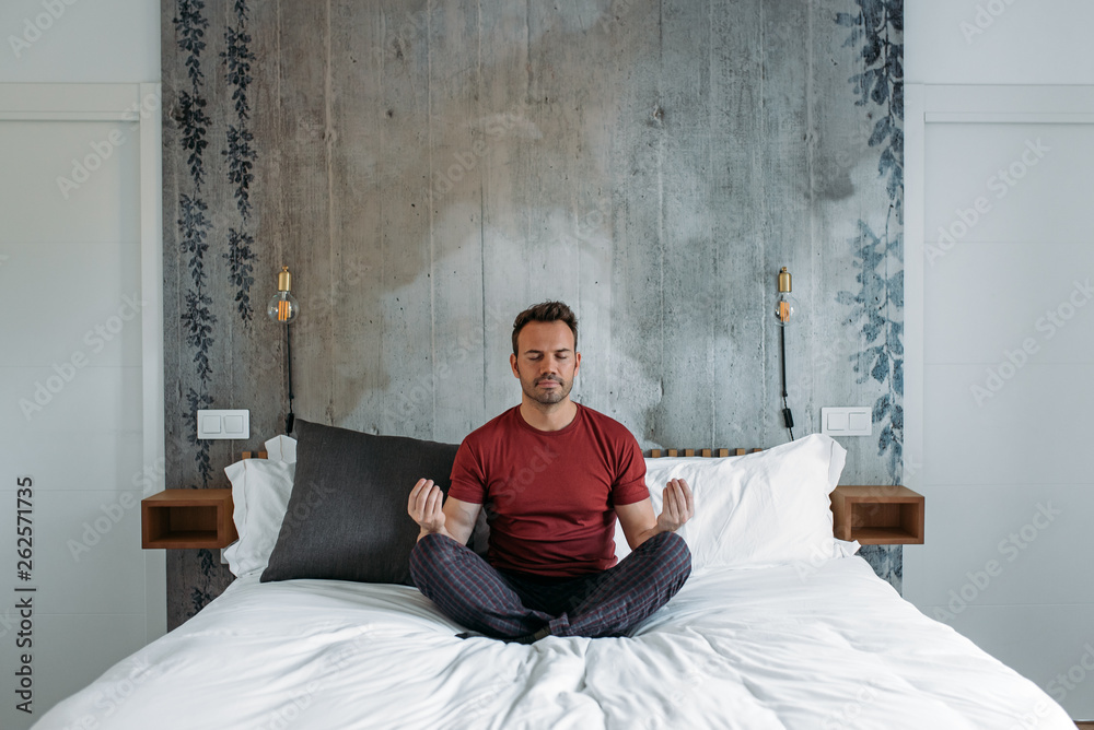 Fototapeta premium Attractive man on bed meditating