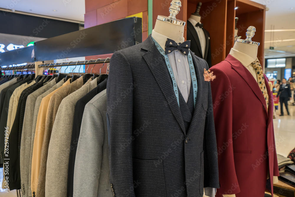 Suits with shirts on hangers on wooden background