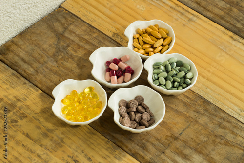 Drugs in the form of capsules, tablets and gelatin in oyster-shaped bowls on dirty wooden background