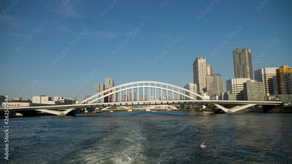 View from boat sailing in sea water with Kachidoki bridge and skyline in background in Tokyo, Japan at daytime on blue sky View from boat sailing in sea water with Kachidoki bridge and skyline in background in Tokyo, Japan at daytime on blue sky