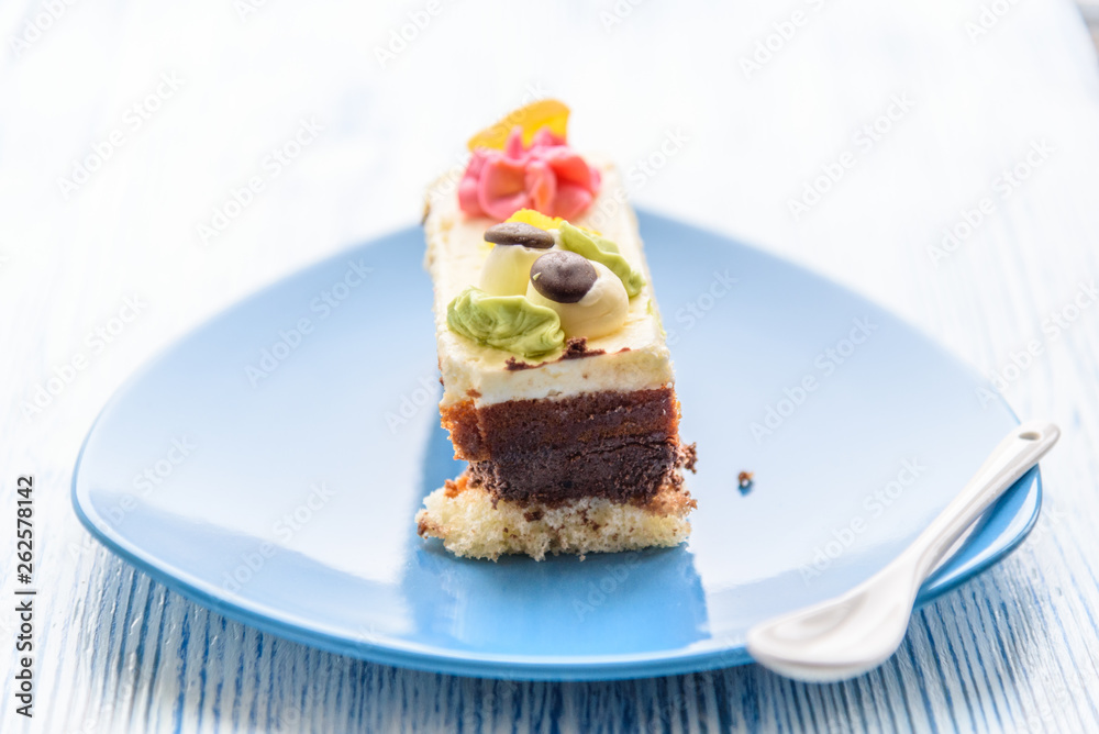 Cake with cream photographed close-up on a blue plate on a wooden background. Cake with cream photographed close-up on a blue plate on a wooden background.