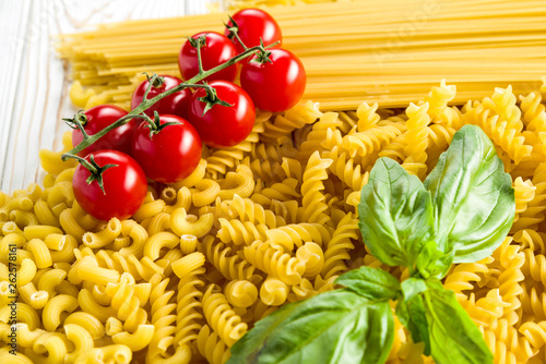 small pasta for soups, curly pasta and basil leaf with tomatoes on the table