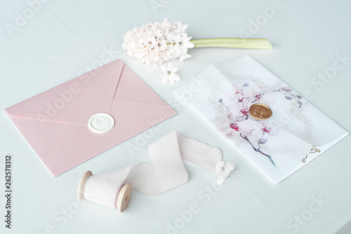 Wedding invitation as a decorated letter on a white tablecloth with a flower arrangement