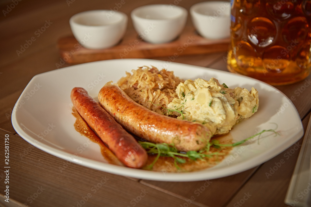 sausages with potatoes and sauerkraut with a beer on the table overlooking the lake sausages with potatoes and sauerkraut with a beer on the table overlooking the lake