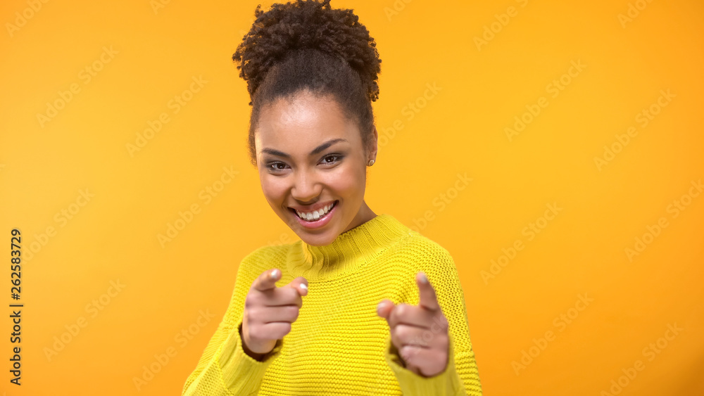 Pretty smiling black lady showing I choose you gesture into camera, close up