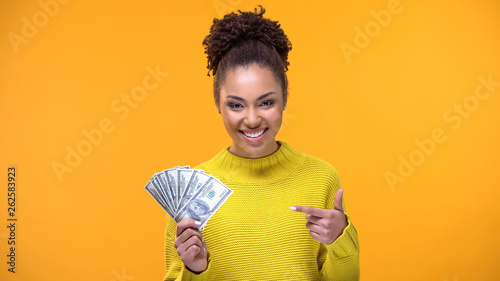 Smiling young lady pointing at dollar banknotes in hand, bank credit, earnings photo