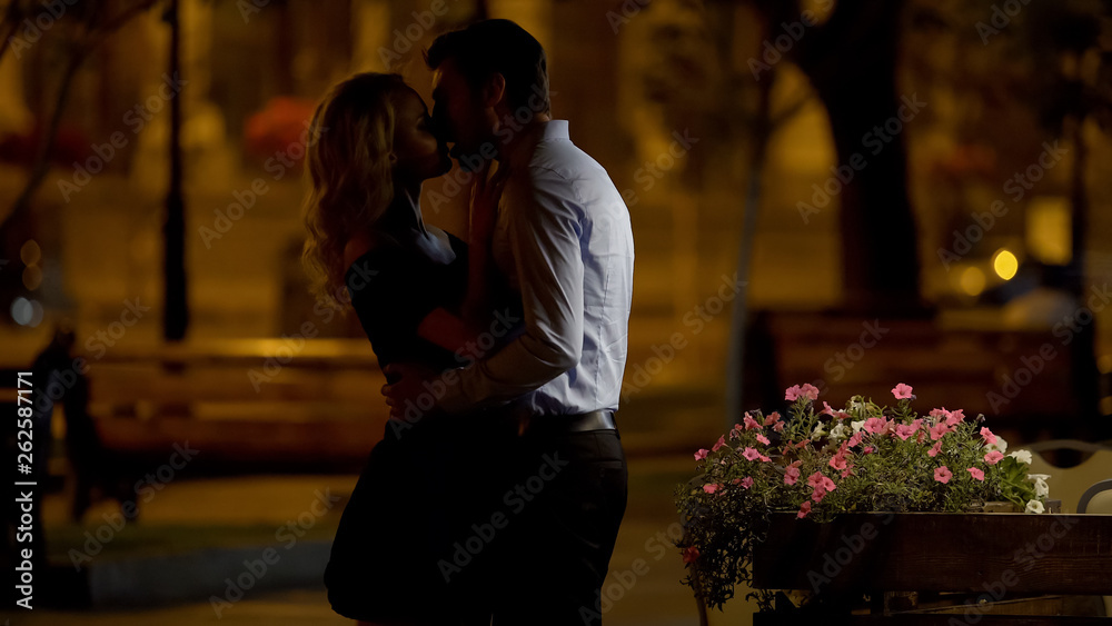 Beautiful couple cuddling and kissing tenderly in park, evening date, love