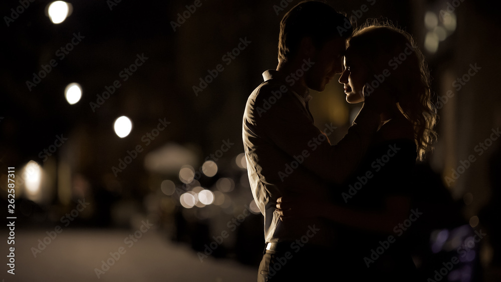 Silhouettes of loving couple embracing each other in the street ...