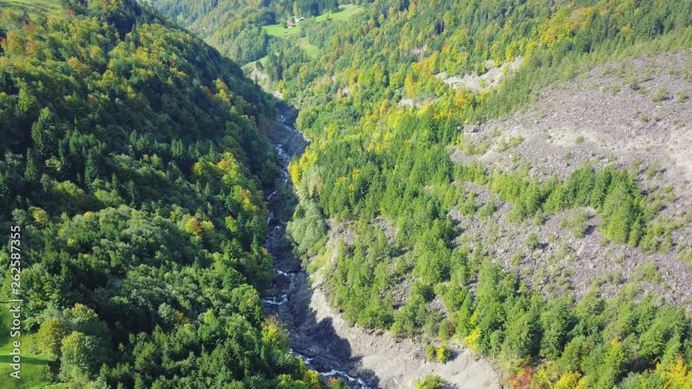 Aerial view of deep valley with wild river. Smooth and stabilized footage from drone flying above landscape. Swiss alps in Europe.