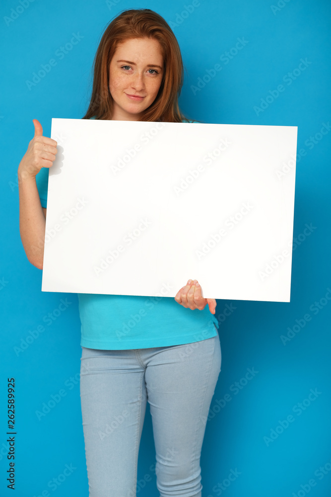 Ginger girl holding a whiteboard on blue background. Ginger girl holding a whiteboard on blue background.