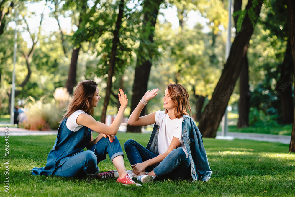 Happy female friends raising hands up giving high five in city park Happy female friends raising hands up giving high five in city park