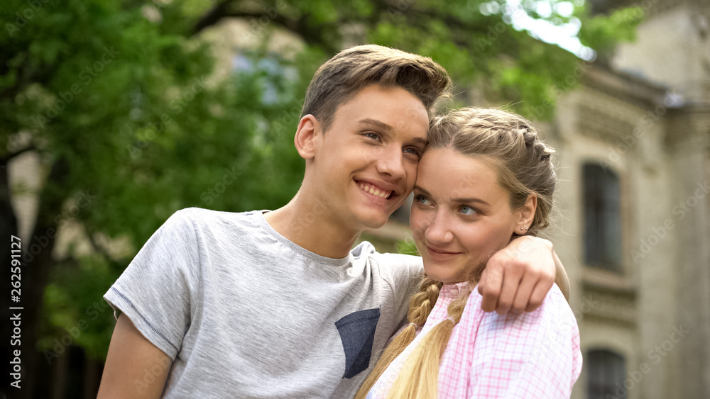 Couple of shy happy teenagers embracing, first relationship, studentship Couple of shy happy teenagers embracing, first relationship, studentship