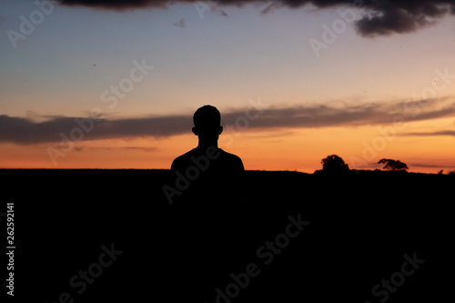 Man watching sunset with silhouette arches in summer © Naiara