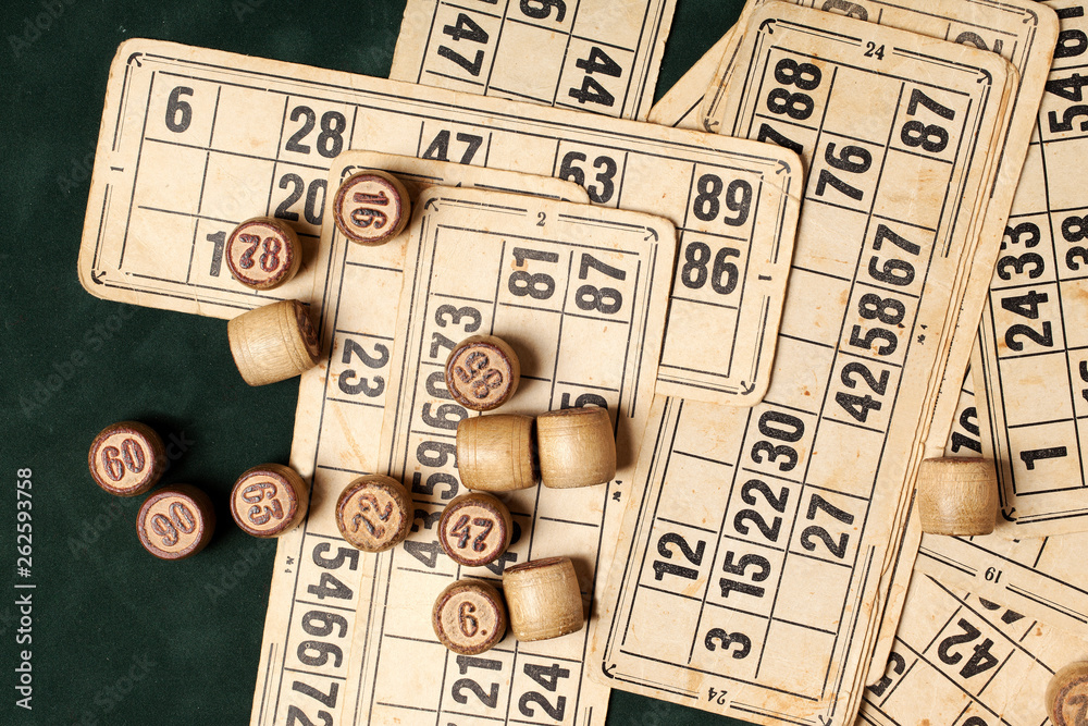 Naklejka premium Table game Bingo. Wooden Lotto barrels with bag, playing cards for Lotto games, games for family on green background