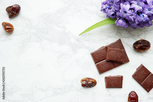 Black chocolate and dates on a marble background, top view