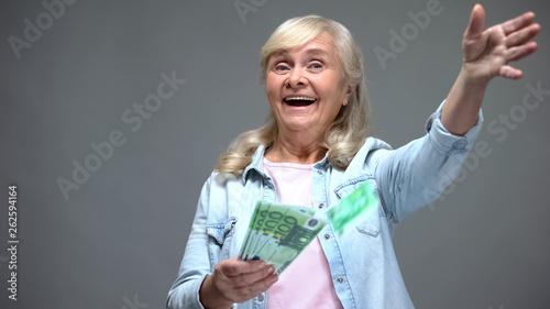 фотографія Cheerful senior female throwing euro banknotes, wasting money, loan service