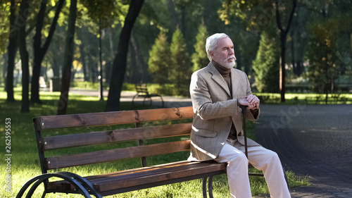 Pensioner with walking stick resting, sitting in park and enjoying warm weather