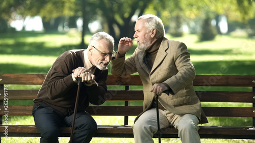 Senior gentlemen talking to his hearing impairment old friend, health problems photo