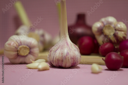 Healthy vegetables on a pink background. Fresh garlic (allium, Bulbus Allii Sativ) is a real storehouse of nutrients and trace elements. Red sweet onions (solaninum) - natural antioxidant. Red radish  photo