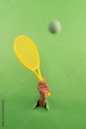 tennis racket on a green background, creative. torn background. hand in texture photo