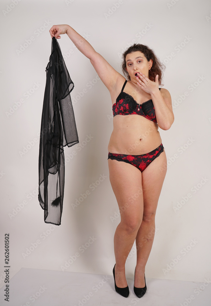 feminine chubby woman with plus size body in black lingerie posing on white  background in Studio Stock Photo