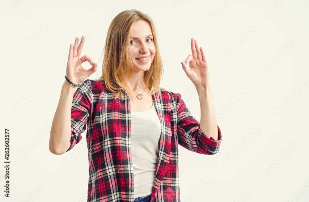 That's cool! Beautiful happy young woman shows fingers ok sign standing on a light background. That's cool! Beautiful happy young woman shows fingers ok sign standing on a light background.