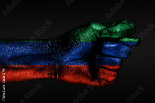 A hand with a painted Dagestan flag shows a fig  a sign of aggression  disagreement  a dispute on a dark background.