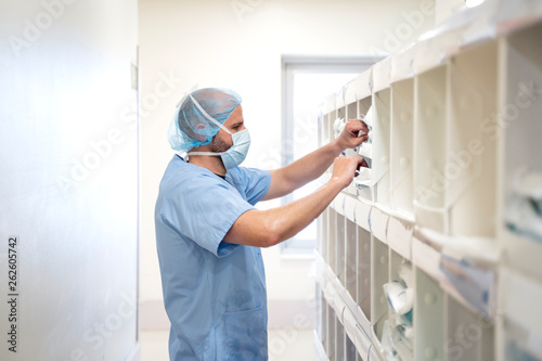 Foto Doctor taking medication from a bookshelf.