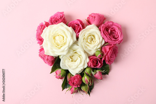 Beautiful roses in shape of heart on color background © Atlas