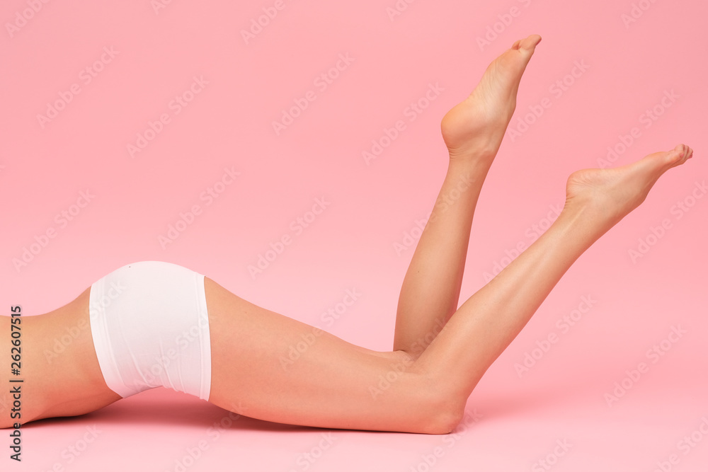 Picture of female, long legs isolated on pink background.