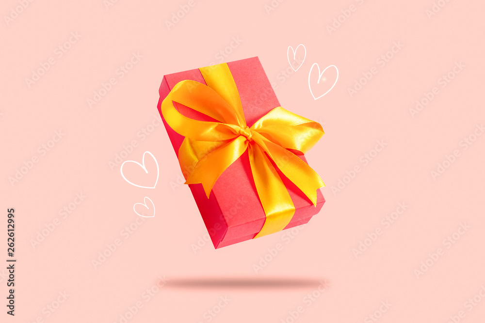 Flying gift box on a light pink background with hearts. Holiday concept, gift, sale, wedding and birthday.