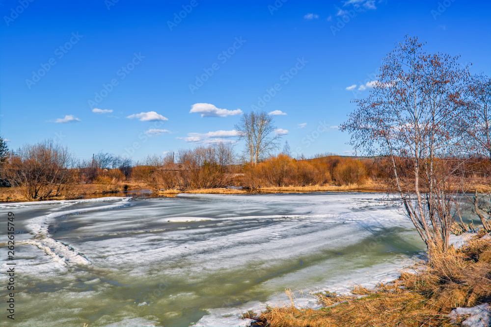 Early Spring landscape melts ice on a small river at the edge of the village. Early Spring landscape melts ice on a small river at the edge of the village.