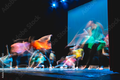 Group of dancer in colored clothes dancing on the stage in long exposure photo
