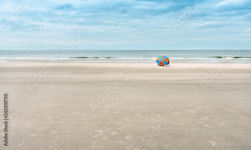 Fototapeta Naklejka Na Ścianę i Meble -  One beach umbrella for tourists on a wide, sandy beach