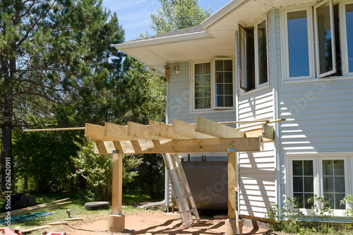 A deck is under construction in the backyard of a split entry home