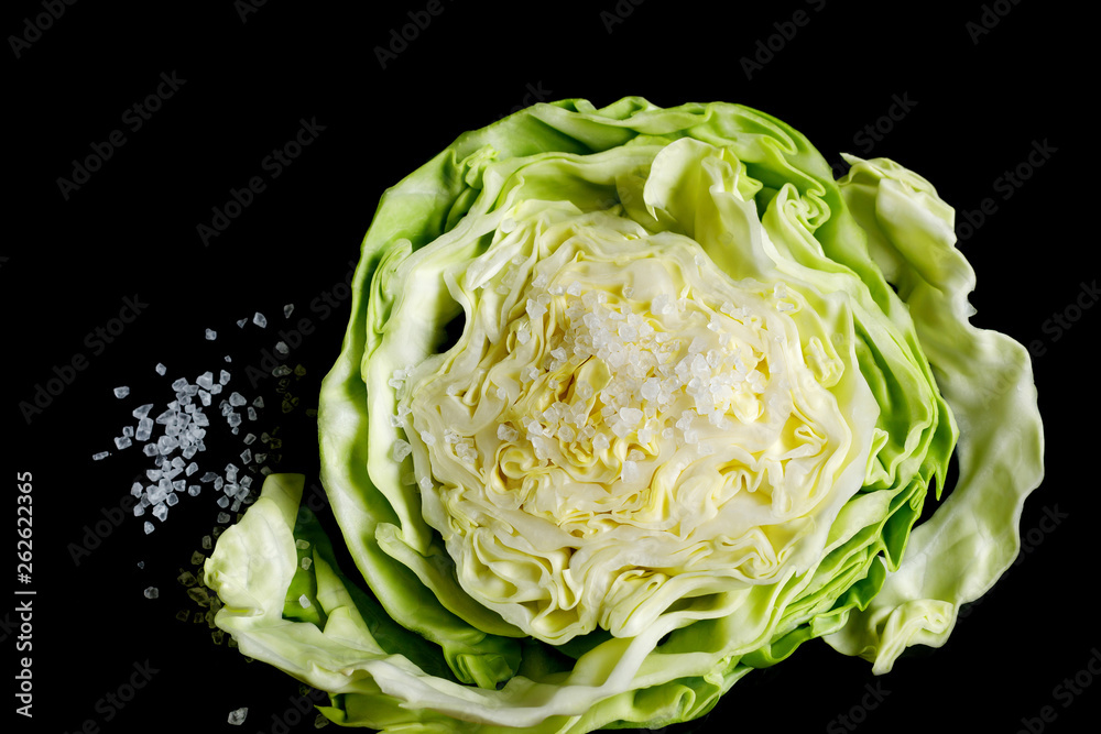 white cabbage slice and coarse sea salt on a black background.