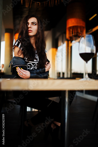 Young curly woman enjoying  her wine in a bar.