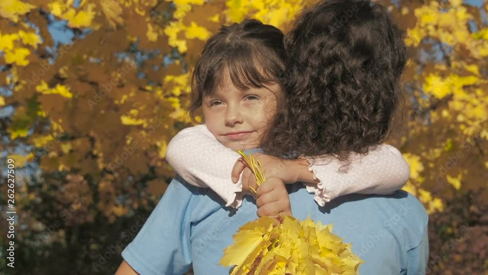 Portrait of a child hugging mother. Yellow maple leaves on the tree. Portrait of a child hugging mother. Yellow maple leaves on the tree.