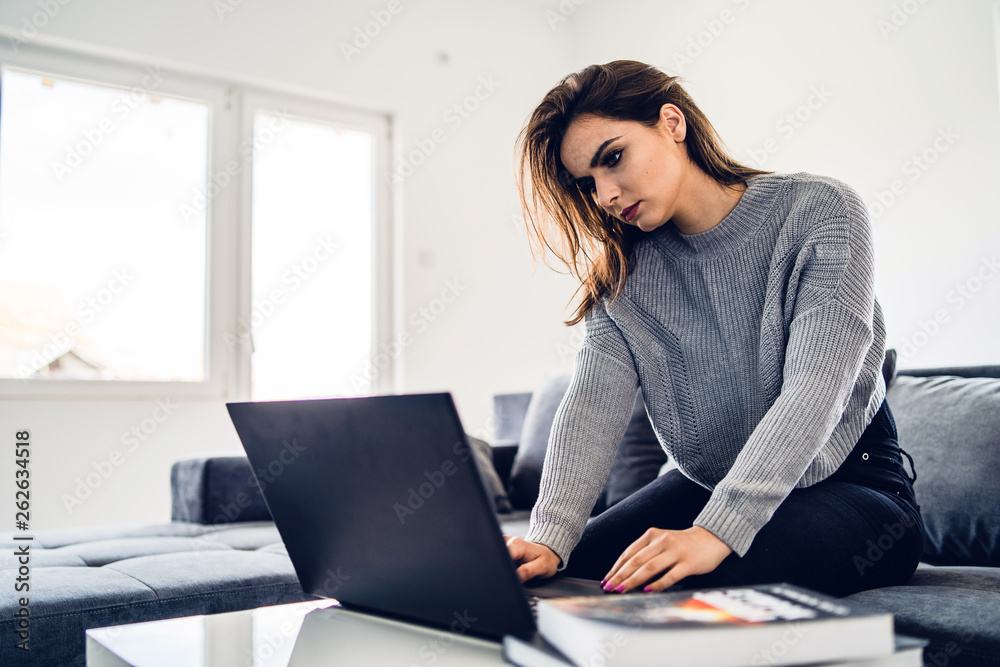 Young woman sitting on the bed using laptop at home searching internet study working Young woman sitting on the bed using laptop at home searching internet study working