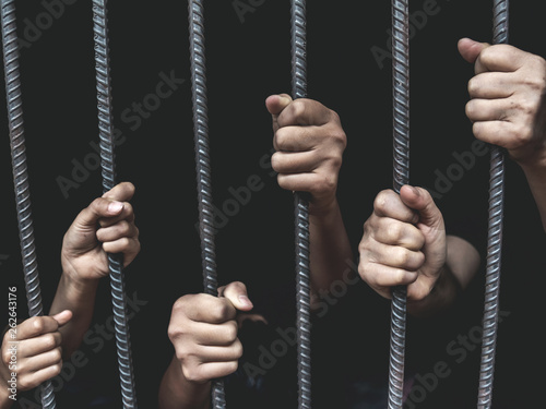 Human hands holding a steel cage in old iron bar. children and women prison and prisoner concept