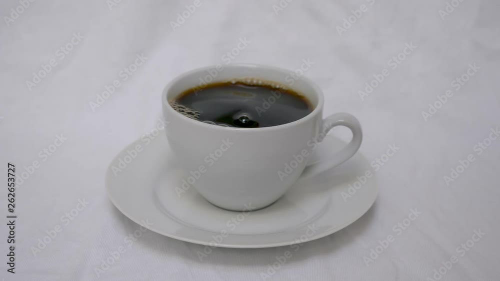 Pouring sugar into white coffee cup with coffee on white saucer with white background Pouring sugar into white coffee cup with coffee on white saucer with white background