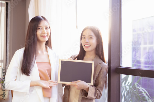 young Asian business woman holding a chalkboard.Successful business woman happy and smile.Idea note on blank blackboard.