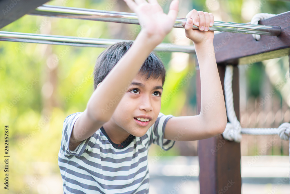 Little Asian toddler boy climbing on the rope at playground