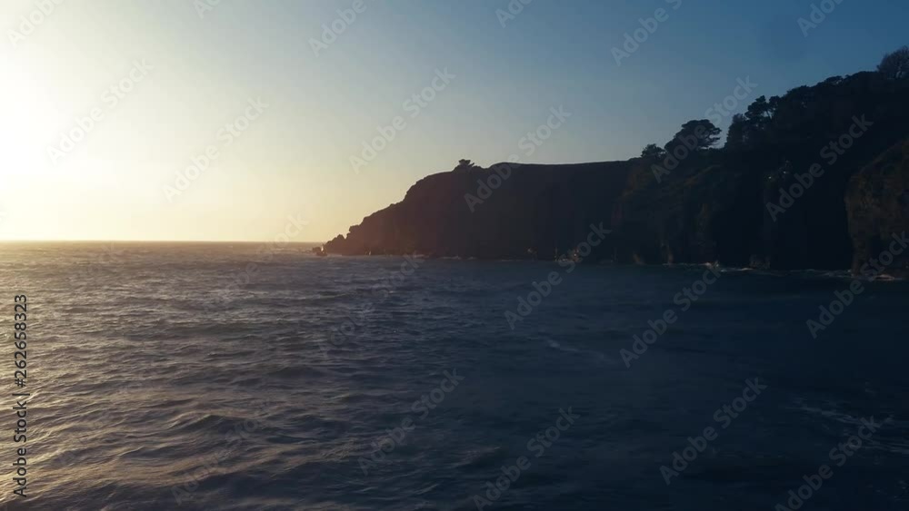Drone captures a setting sun at golden hour over a lonely cove. Haze and setting sun create a dreamy and surreal vibe. Drone captures a setting sun at golden hour over a lonely cove. Haze and setting sun create a dreamy and surreal vibe.