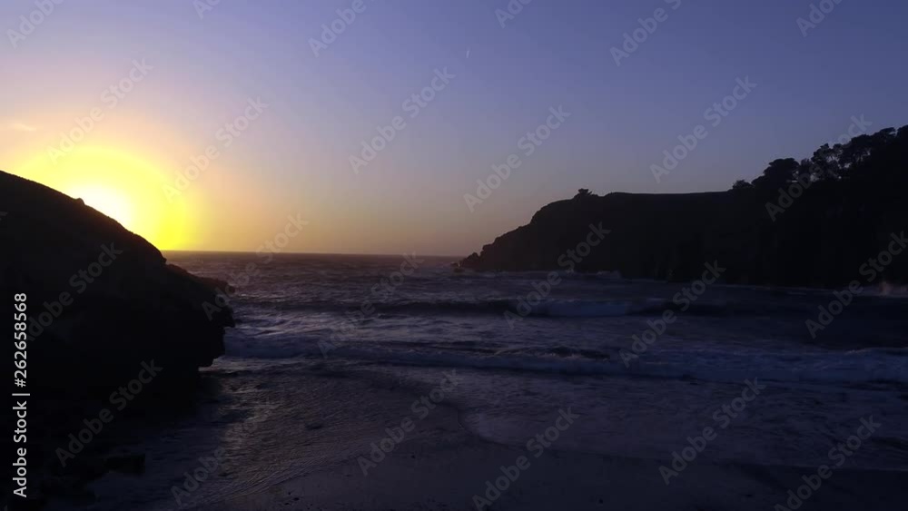 Drone captures a setting sun at golden hour over a lonely cove with a rocky beach. Haze and setting sun create a dreamy and surreal vibe. Drone captures a setting sun at golden hour over a lonely cove with a rocky beach. Haze and setting sun create a dreamy and surreal vibe.
