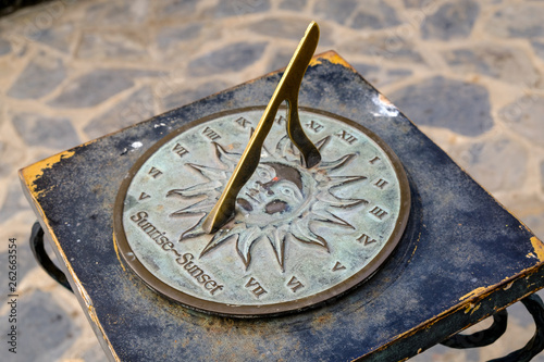 Close-up of a brass sundial mounted on a stone plinth in a garden, Sundial in the Summer sun.